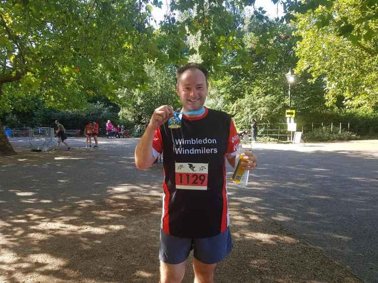 John Gorst lifts his finishers' medal aloft after completing the RunThrough Events 10km race