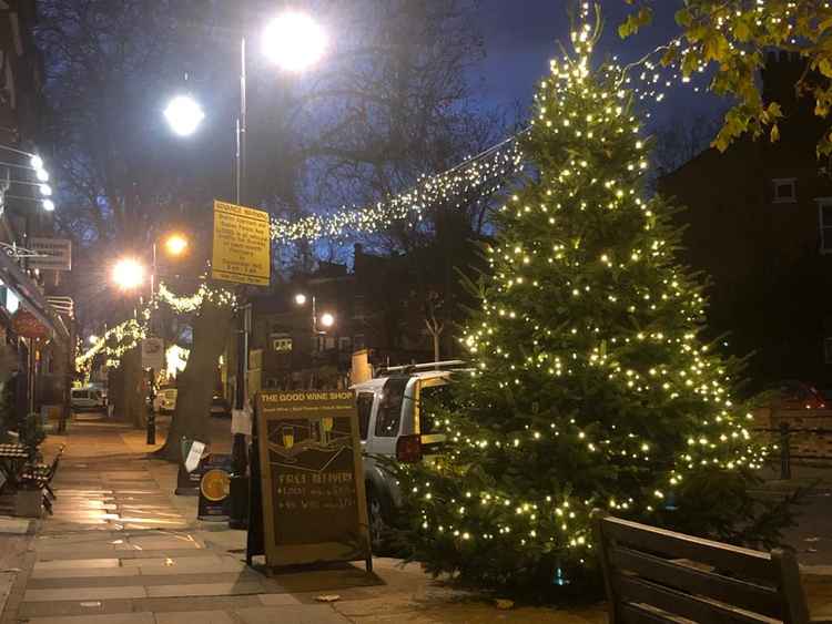 A Christmas tree and lights decorate the village