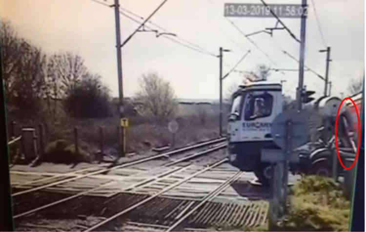 The level crossing camera view of the stationary lorry and partly lowered level crossing barrier (highlighted) caught by equipment on the back of the lorry. The approaching train is hidden by the lorry.