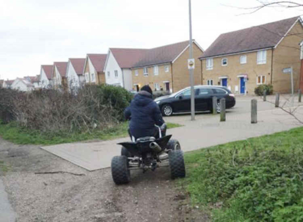 A quad bike racer racing across footpaths onto the estate