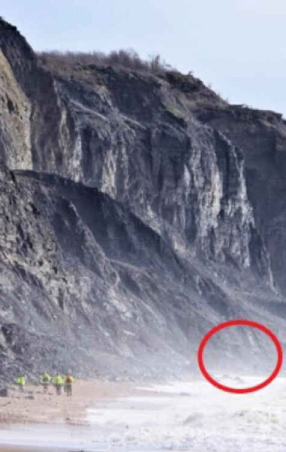 Coastguards approach the fossil hunter, shown faintly circle in red, on Charmouth beach