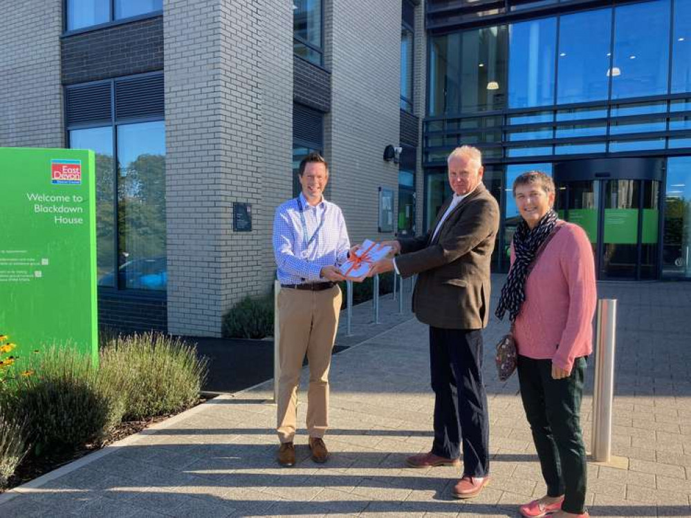 Ian Priestley, chair of the Colyford Residents' association, presents the petition to Henry Gordon Lennox of EDDC, with the assistance of residents' association committee member Annie Thompson