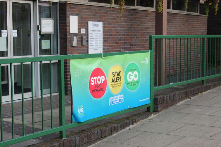 A Cheshire East Council sign urging the public to heed caution with COVID, outside Market Square's Congleton Library.