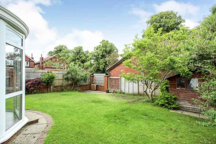 The enclosed rear garden is predominantly laid to lawn along with a corner patio area and with some trees.