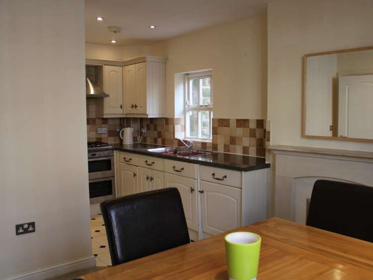 This cosy rental home has a fully fitted Kitchen with gas hob, electric oven, washer/dryer and fridge. Adjacent is the open plan Dining Area with dining table and 4 chairs. (Image - Belvoir Macclesfield)