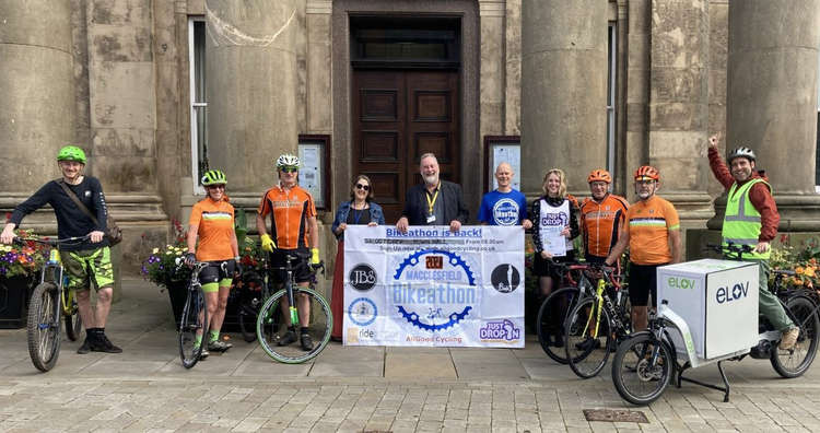 Macclesfield cycling influencers Macc Wheelers (orange), ELOV (right), and Darren Allgood (blue) pose with Macclesfield Town Council's Mayor (lanyard) and Events officer Abigail Sherratt.