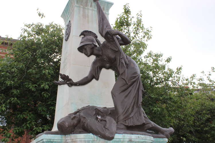 The statues show a grieving woman at the top, and Britannia laying a wreath over a fallen soldier at the bottom.