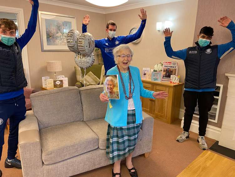 Agnes cheers with her letter from the queen and new friends from Macclesfield FC.