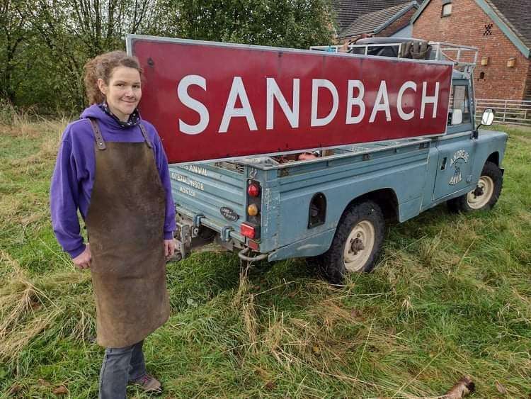 Blacksmith Andrea Hughes with the historic sign she has restored