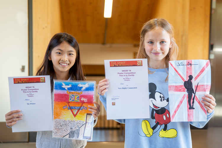 Mihiro (left) and Evie (right) with the posters and prizes