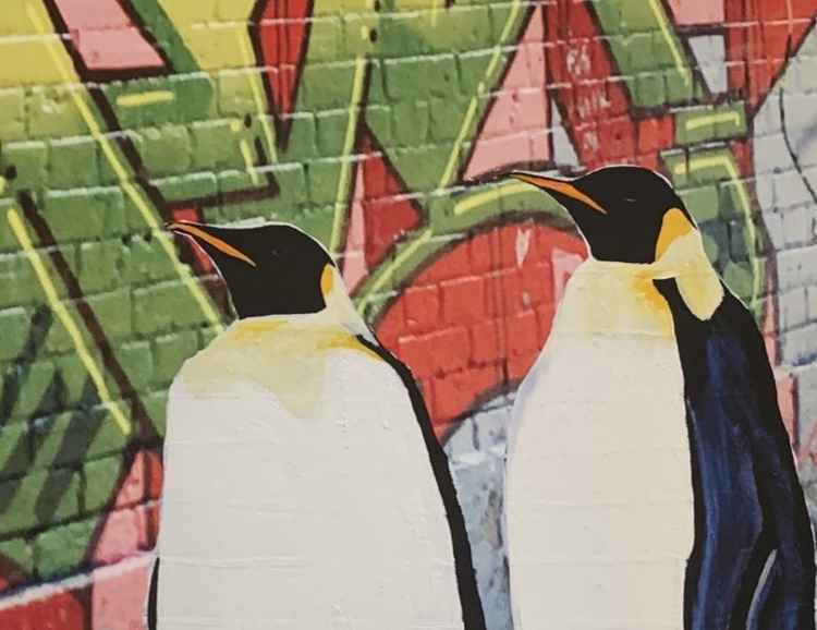 A painting of two emperor penguins by a colourful graffiti wall