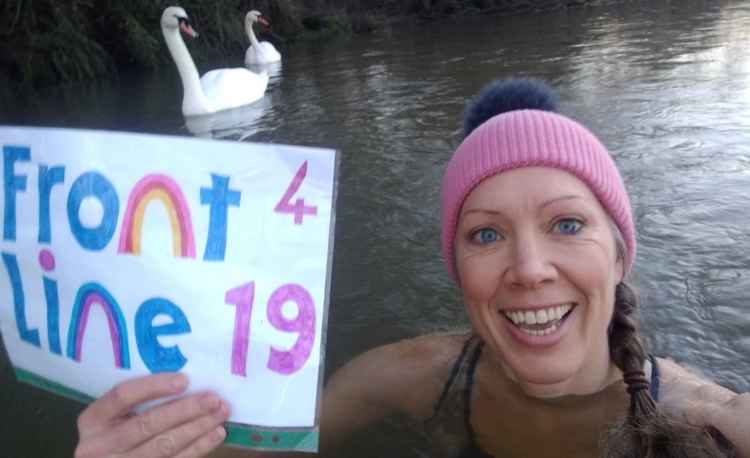 Susi holds up a poster saying Frontline 19 while braving the cold water of the Thames / Photo: Susi Halley