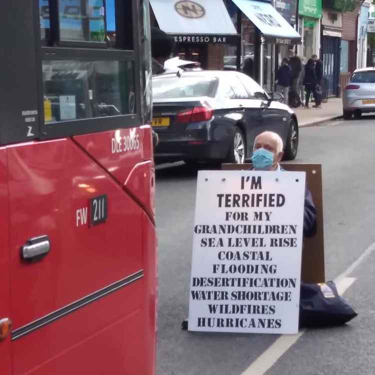 Another view of Pat as a bus approaches the area he is sitting / Photo credit: Extinction Rebellion Richmond