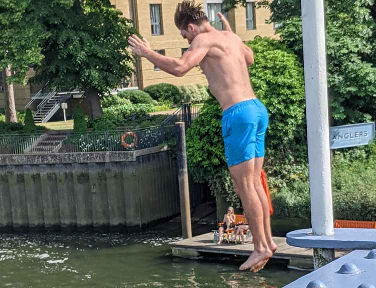 A young male jumps off the footbridge at Teddington Lock