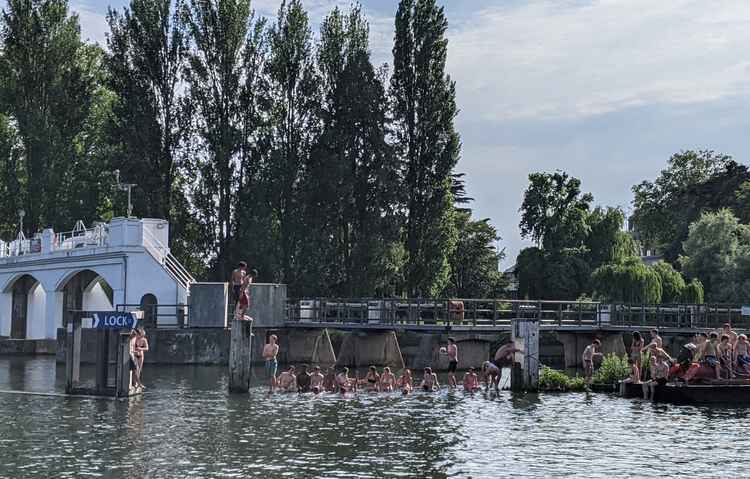 Groups sit near Teddington Weir, some on inflatables brought to the area