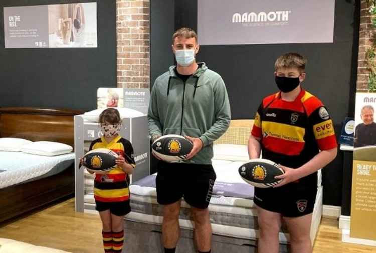 Honiton Rugby Club juniors Edie and Josh with Ollie Devoto, holding the signed rugby balls that will be auctioned to raise funds for the club