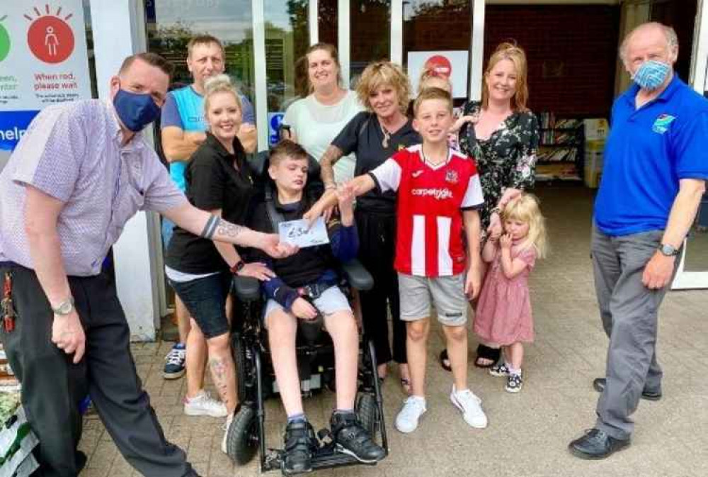 Duncan Sheridan-Shaw (pictured left) hands over the cheque outside Tesco Honiton. Photo credit: Vernon Whitlock