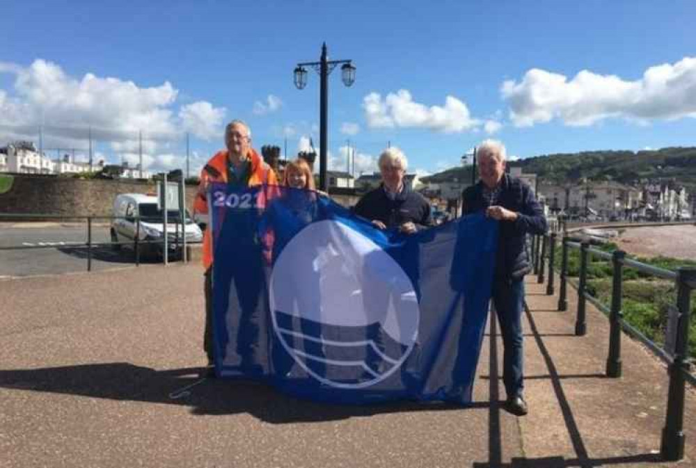 Cllrs Denise Bickley, vice-chair of Sidmouth Town Council Cllr Chris Lockyear, and Cllr Geoff Jung raising the Blue Flag for Sidmouth