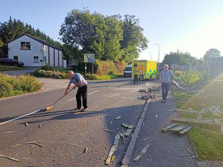 The house's owner and a police officer clear debris from the road