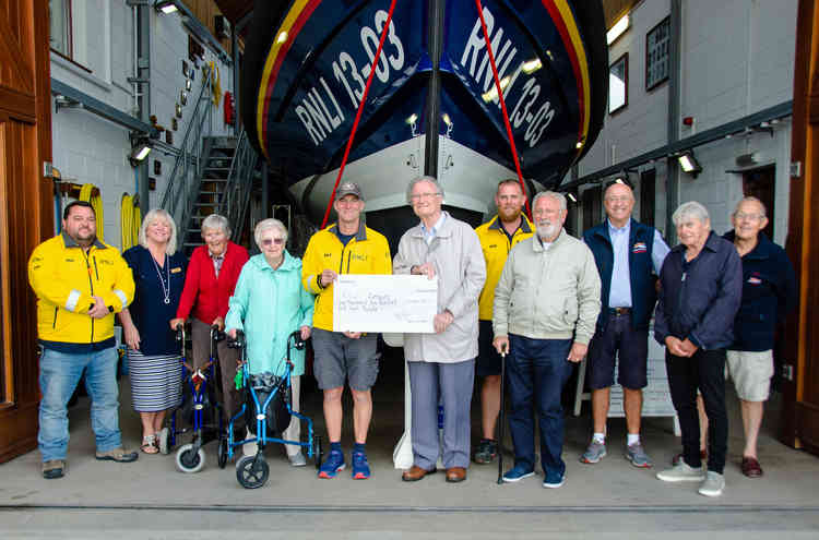 Residents of Manor Lodge Residential Care Home present their cheque to Exmouth RNLI Coxswain, Steve Hockings-Thompson at Exmouth RNLI Lifeboat Station flanked by other volunteer crew members and staff.  Credit : John Thorogood / Exmouth RNLI