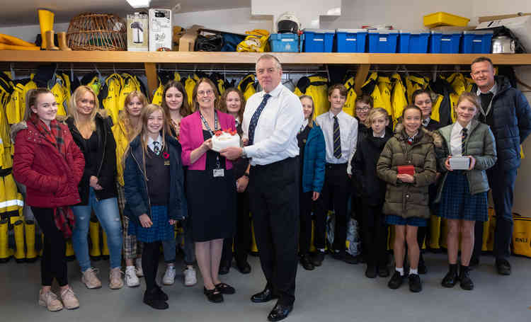 Students from Clyst Vale Community College present their cake for Exmouth RNLI Crew to Lifeboat Operations Manager, Mike Gall