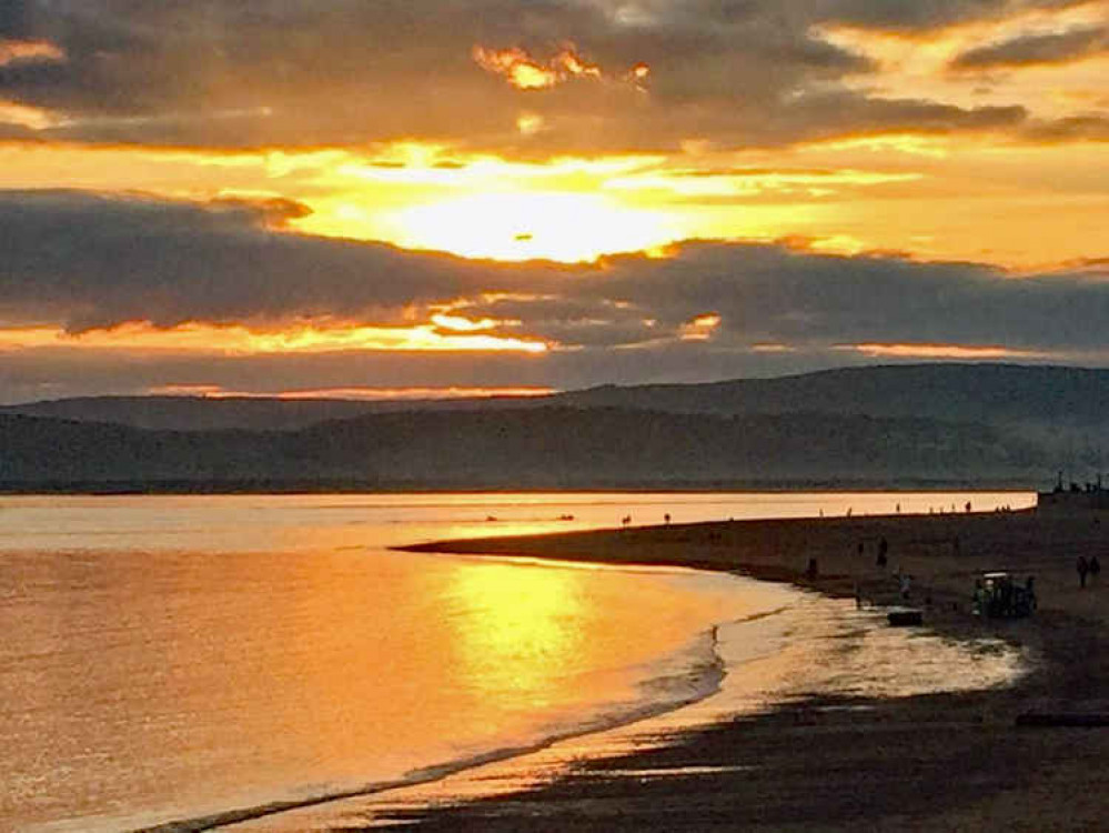 Exmouth RNLI lifesavers in action towing the jetski in the distance with the RNLI shore crew on the beach.