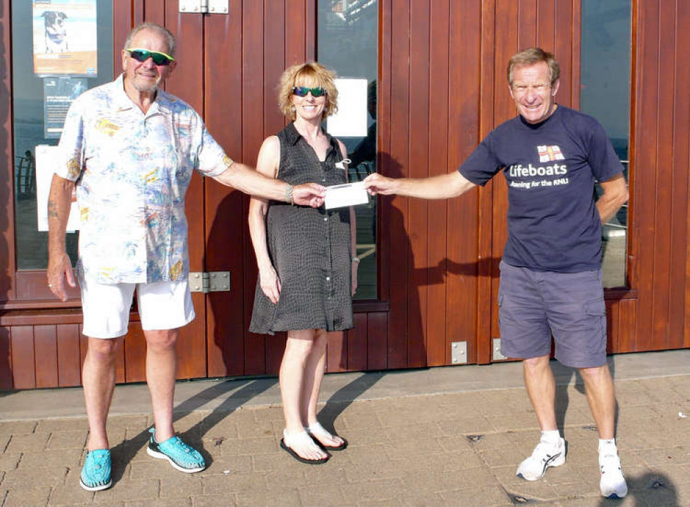 Left, Ray and Gina Lovegrove present the cheque to right, Exmouth RNLI Fundraising Chair, Des White. Credit : Alison White / RNLI