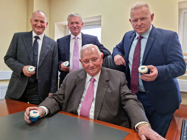 Swansway founder and chairman Michael Smyth (sitting front) and staff mark the occasion with cupcakes.