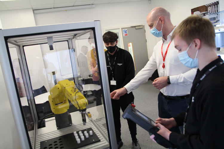 MP Kieran Mullen watches a robotic arm demonstration from Cheshire College students.