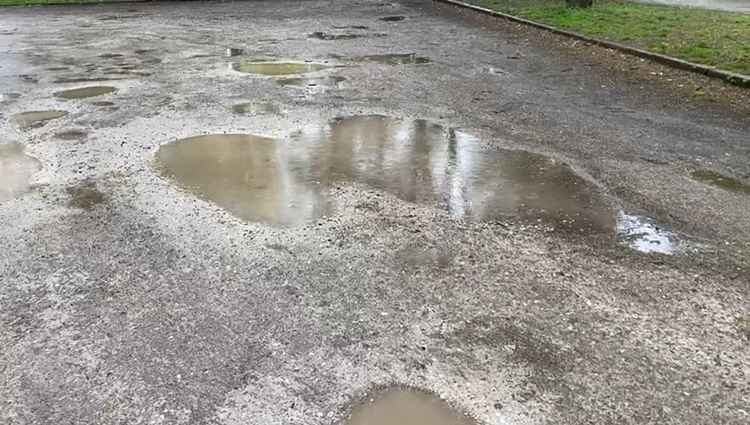 The car park's surface is pitted with pot holes.