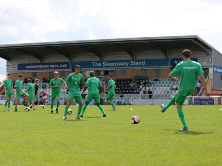 Nantwich Town's players warm-up in front of the newly-named Swansway Stand.