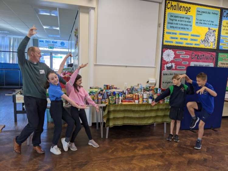 The Rev. Paul North of St Mary's Church offers children at Wistaston Church Lane Academy a helping hand with their collections.