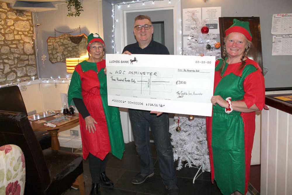 Paul Bocker, landlord of The Castle Inn in Axminster, hands over a cheque for £300 to Suzie McFadzean and Janice Cole from Arc