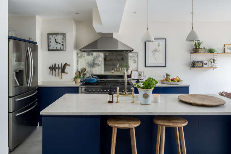 The kitchen is composed of striking blue cabinetry topped with white marble (Image: The Modern House)