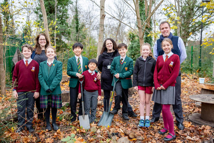 Children at Holy Family Catholic Primary gather with former pupils who now attend St Benedict's to plant a tree in their forest school. (Image: St Benedict's School)
