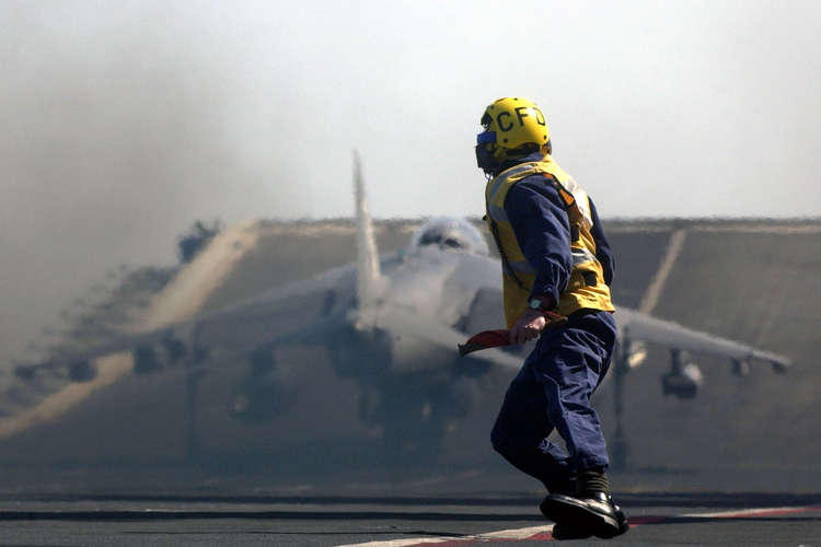 Pictured in 2005 on HMS Invincible, Chief of the Flight Deck then-Petty Officer Doo Facer watches the launch of a Harrier GR7 jet from IV(AC) Squadron RAF.
