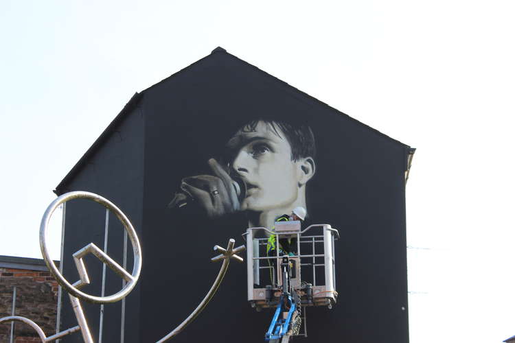 The work in progress mural viewed from the new benches platforms opposite the bus station.