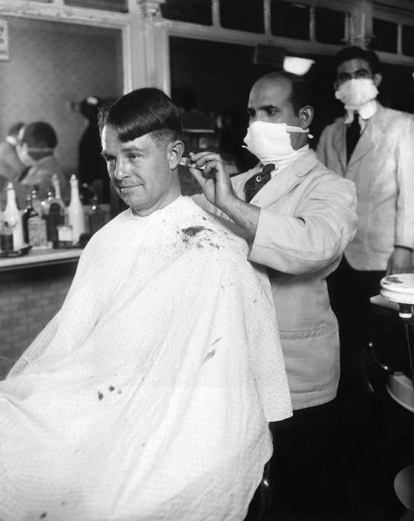 Man Getting Haircut from Barber Wearing Surgical Mask circa 1919. Credit: Getty Images.