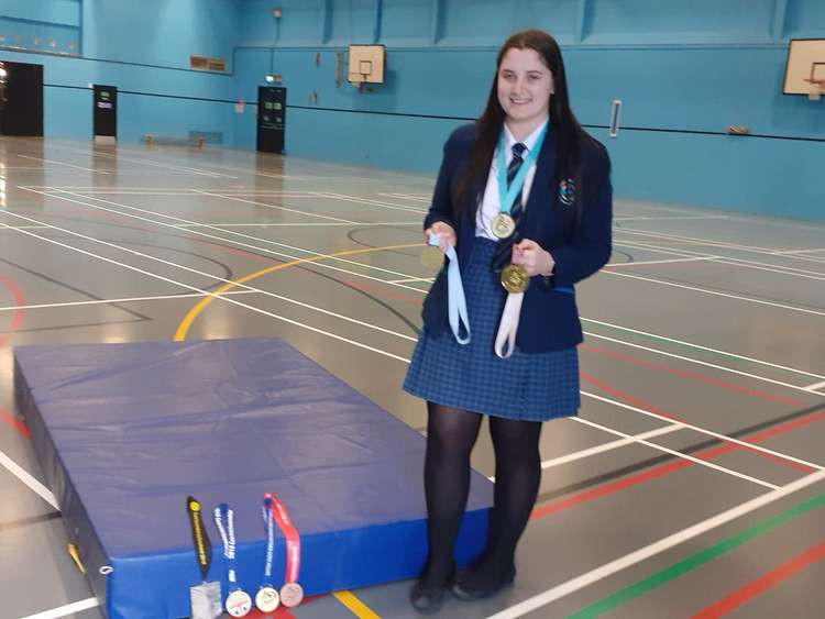 Milly poses with some of her medals in the school's sports hall.