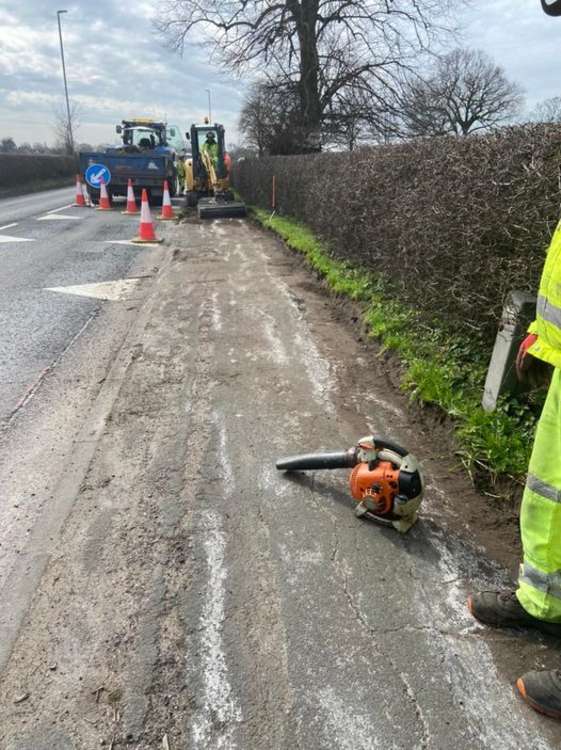 Workmen clearing the overgrown pavement.