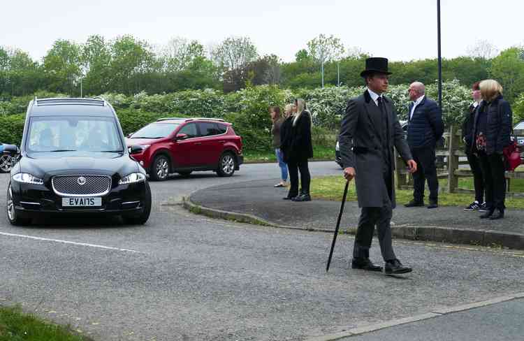 Paying a final respect: The funeral director walks in front of the hearse