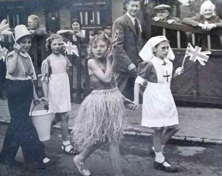 May 8, 1945: June Day, in a nurse's uniform, flag waving at the fancy dress parade