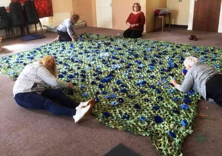 Help sew and sews: Councillor Angie Spencer, foreground, with volunteers creating the net of blue poppies