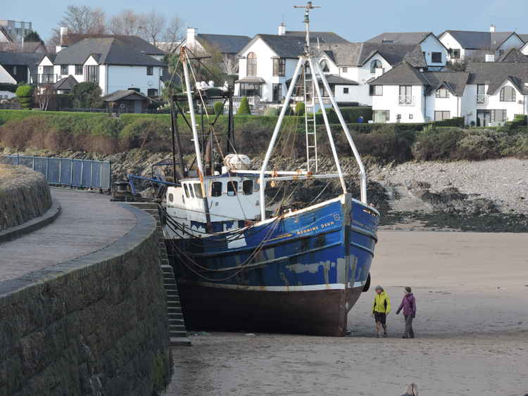 The blue boat is moored closer to the sea at the harbour