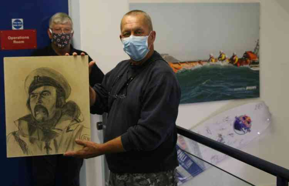 Mark Shephard, grandson of the artist Camille Moore, holding the portrait of John Hodder with lifeboat operations manager Nick Marks in the background.