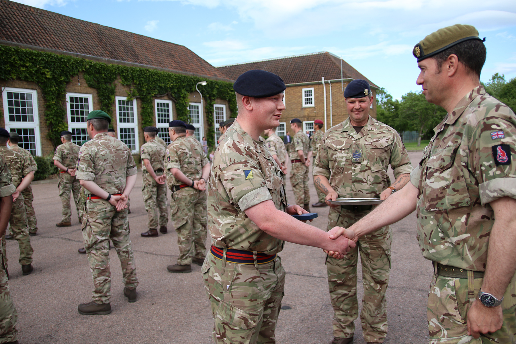 Private Arron Walker, who was the most junior soldier on parade presents the Commander of 7th Infantry Brigade, Brigadier Guy Foden, with his Platinum Jubilee Medal.