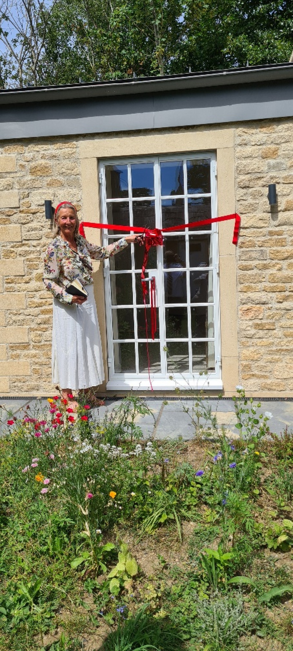 Miriam Cheal, Chairman of the Blue House Trustees, cuts the ribbon in the opening ceremony on 01 August, attended by Trustees, residents, consultants and contractors].   