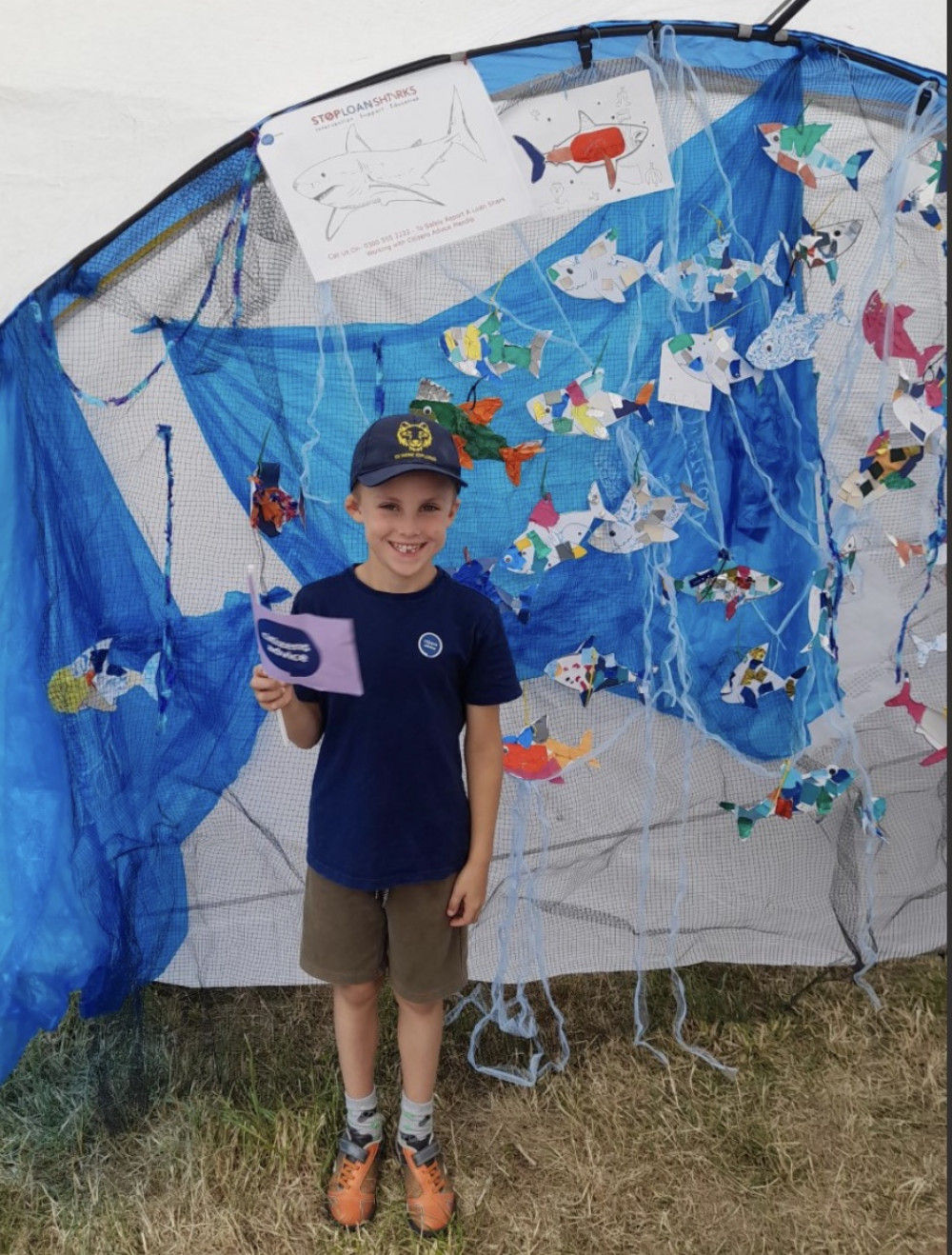 One of the young artists in front of the sharks the children created 