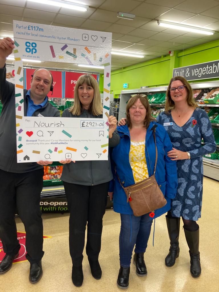 Volunteers from Nourish receive a cheque from Co-op