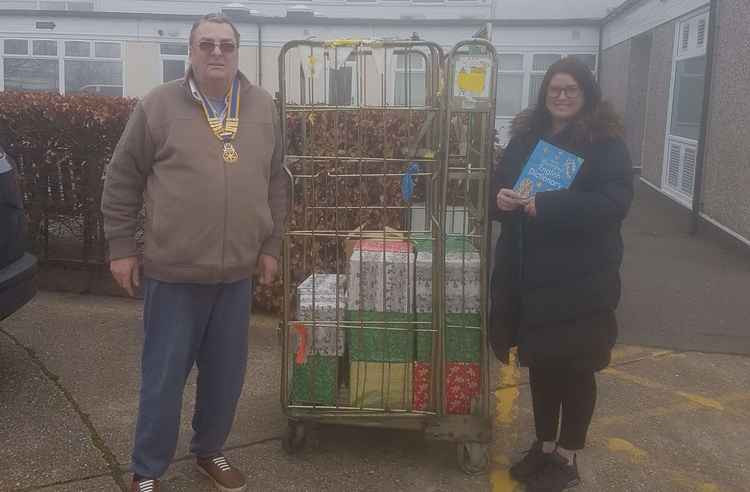 Rotary Club President Malcolm Myles delivers the books to Miss Atkins at the school